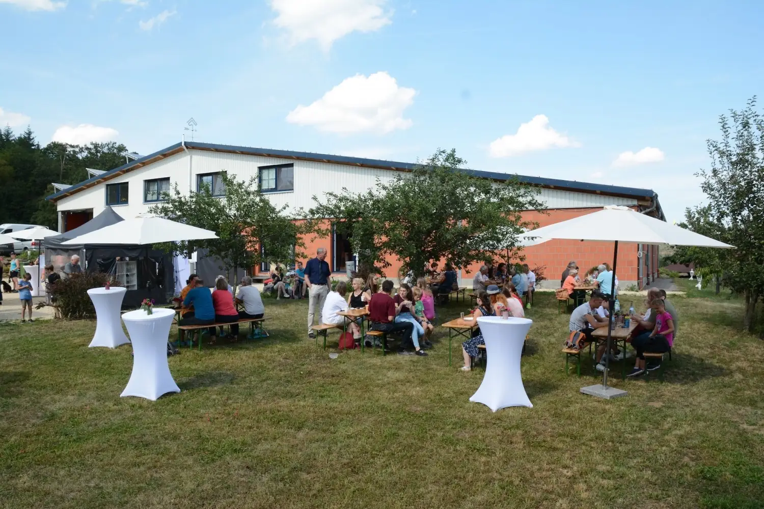 Gäste an Biertischen und Stehtischen im Garten vor dem Barockreitzentrum Heimsheim
