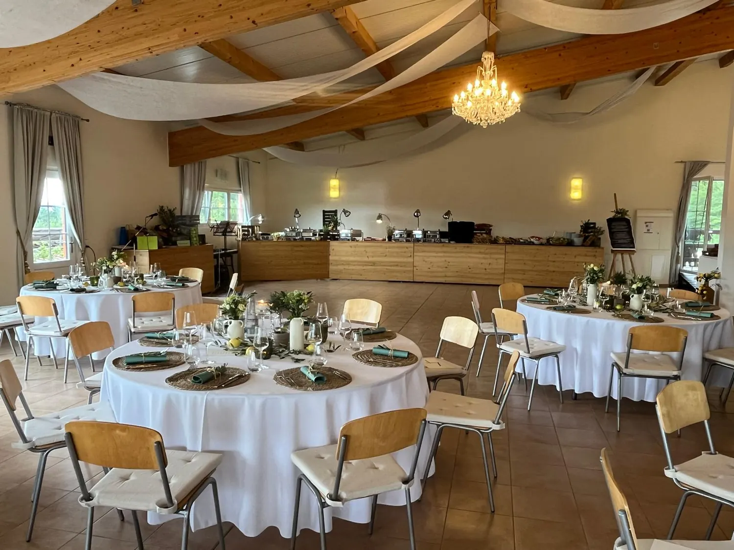 Festsaal des Barockreitzentrums Heimsheim mit runden gedeckten Tischen, Buffet an der Wand und Kronleuchter unter dem Holzdachstuhl