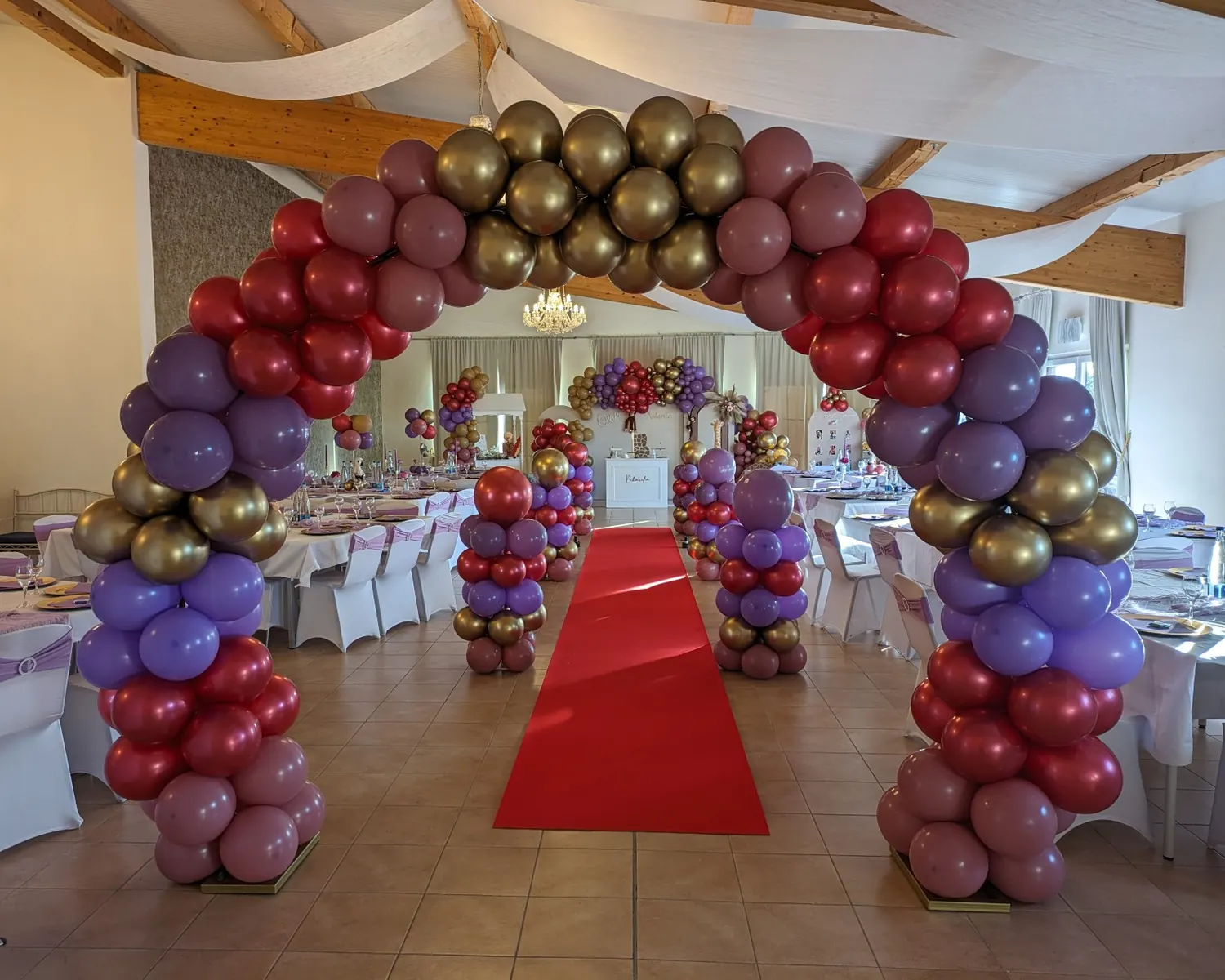 Festsaal des Barockreitzentrums Heimsheim, für eine Geburtstagsfeier geschmückt: Ballonbogen in Gold, Rot und Lila über einem roten Teppich
