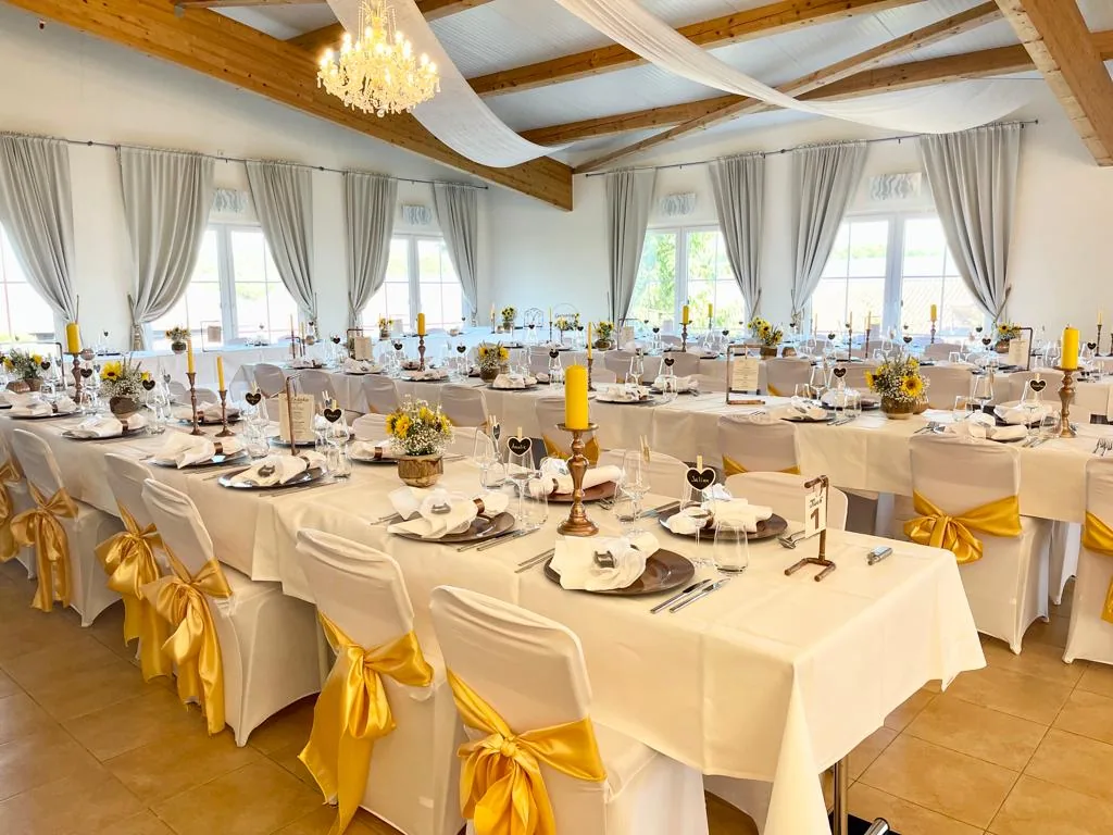 Festsaal „Salle de la Guérinière“ mit langen gedeckten Tafeln, gelben Stuhlschleifen und Kronleuchter