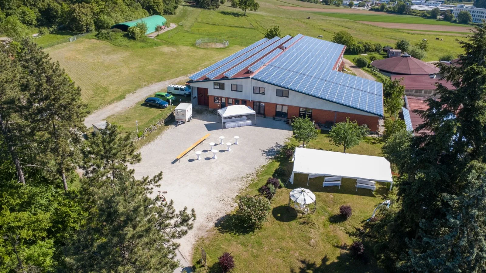 Luftbild des Hofplatzes im Hochzeitsaufbau mit Pavillon, weiß bezogenen Stehtischen und großem Zelt