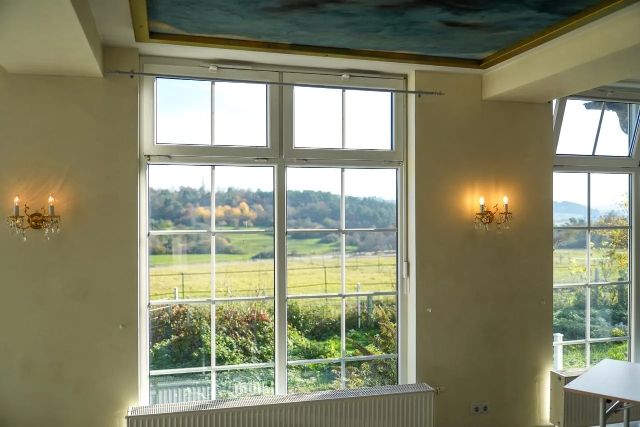 Fenster mit Blick auf die Koppeln, links und rechts vergoldete Kristall-Wandleuchter, oben der Rand des Deckengemäldes